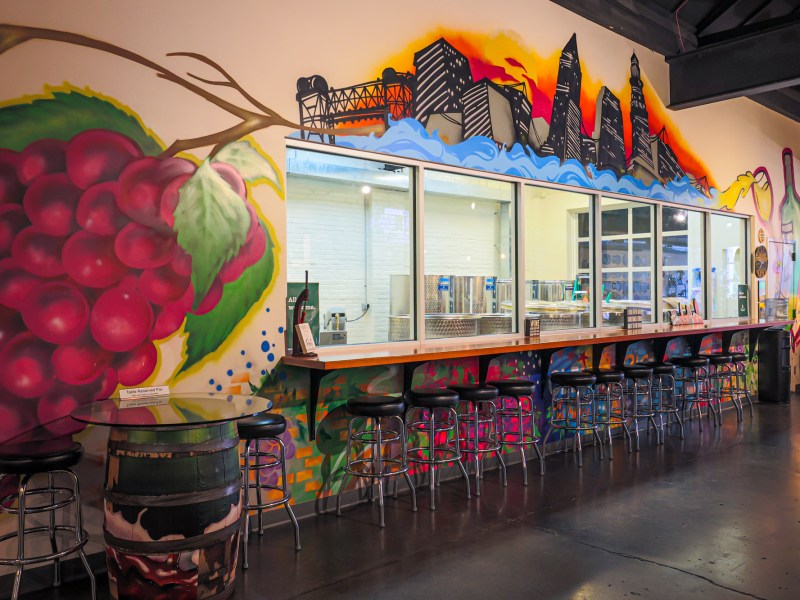 A colorful wall with barstools and a bar