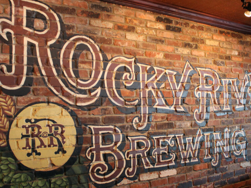 A sign for a brewery on a brick wall.