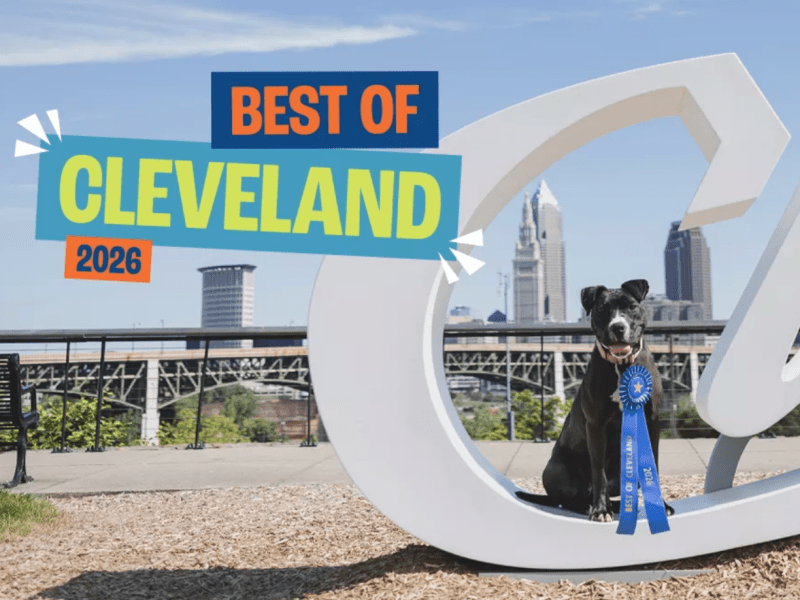 A dog in front of a Cleveland sign and skyline.